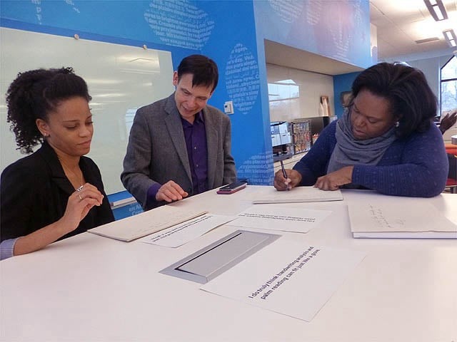 People seated at table writing handwriting samples.
