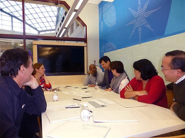 Mister Vibe analyzing the handwriting of a group seated at a table.