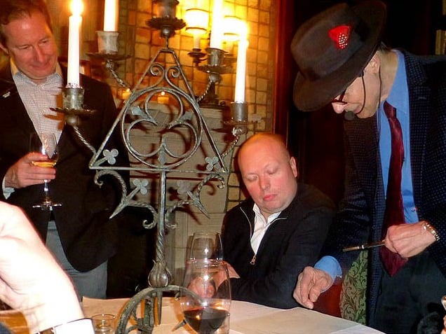 Mister Vibe analyzing the handwriting of a group seated at a table.