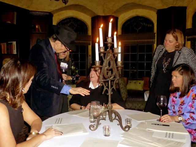 Mister Vibe analyzing the handwriting of a group seated at a table.
